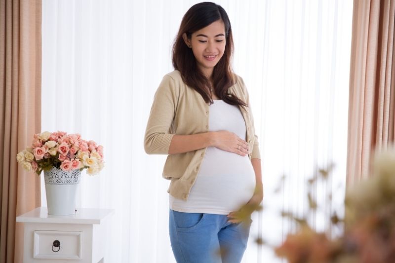 Người phụ nữ chạm nhẹ vào bụng với ánh mắt trìu mến