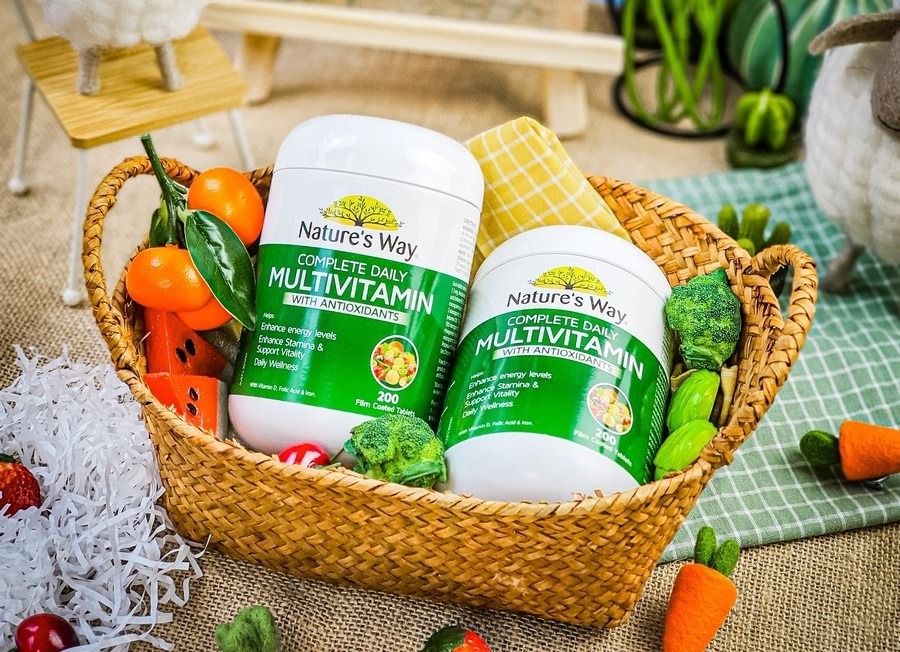 Lọ multivitamin đặt cạnh trái cây tươi và ly nước