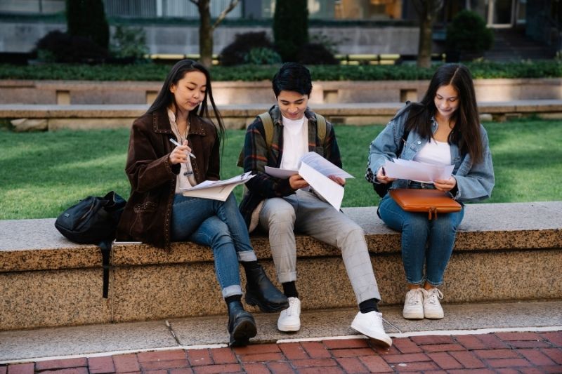 Sinh viên quốc tế tại một trường đại học ở Anh, ngồi trước tòa nhà kiến trúc cổ kính