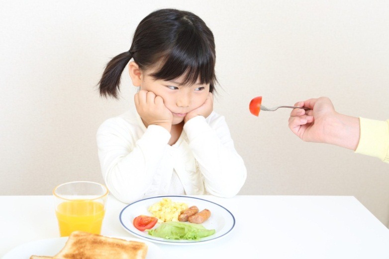 Bé tỏ vẻ không vui khi bị ép ăn thêm trong bữa cơm.