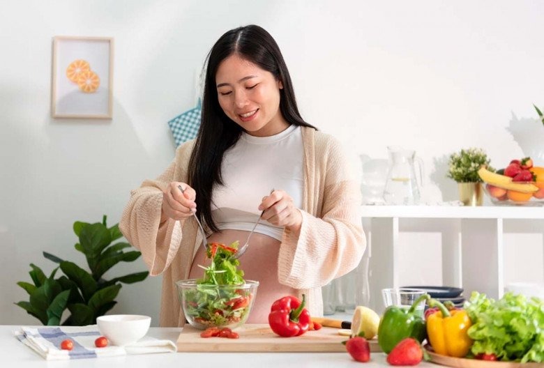 Mẹ bầu ăn salad rau củ trong không gian sáng sủa.