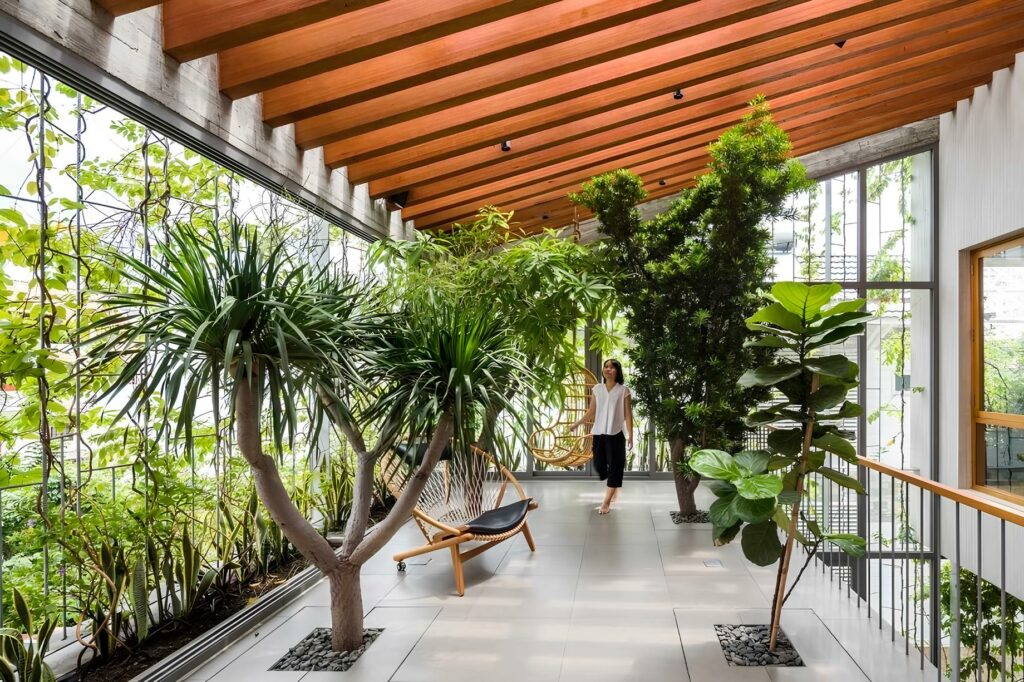 Người phụ nữ thư giãn trong căn phòng sáng sủa, cây xanh bao quanh.